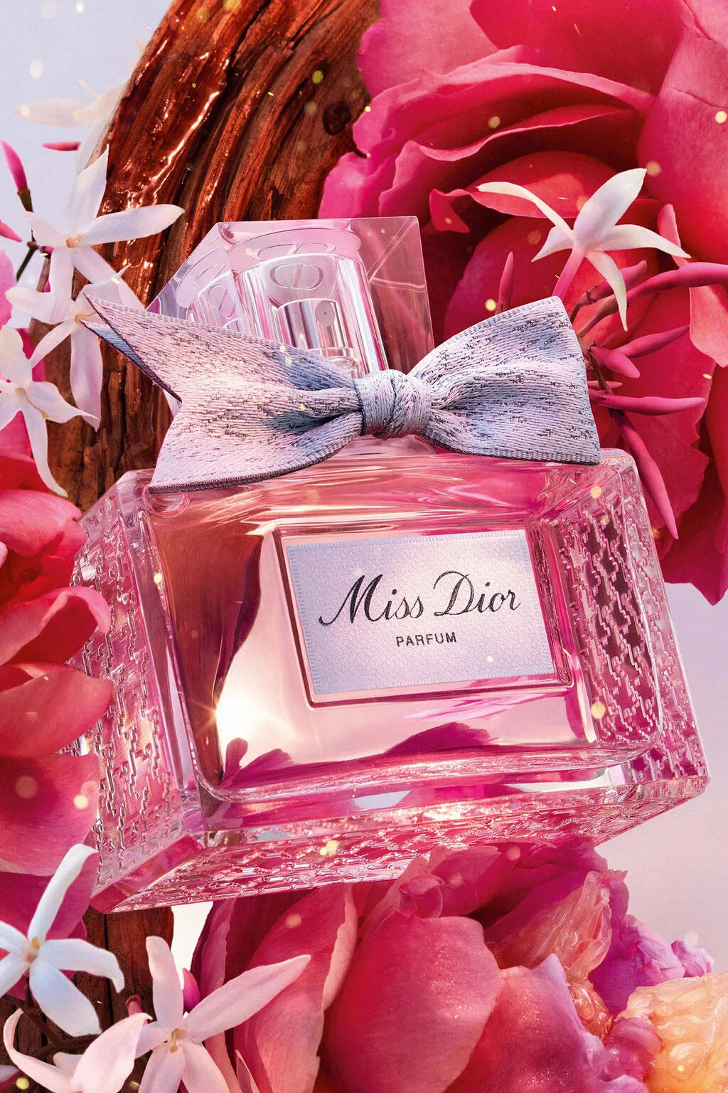 Miss Dior Parfum by Dior surrounded by pink roses and jasmine flowers showcasing its floral and fruity fragrance inspiration.