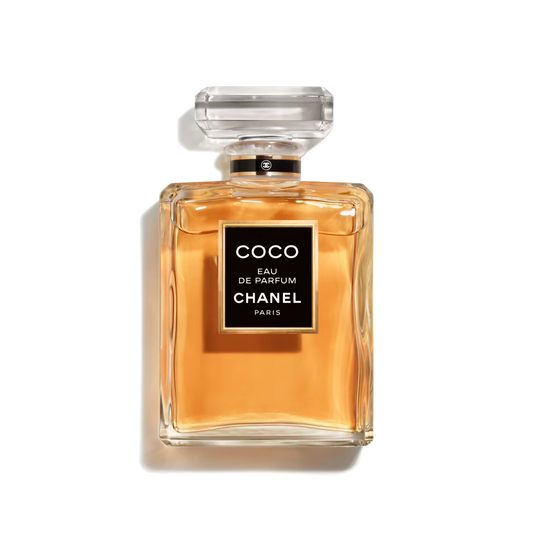 Chanel Coco Eau de Parfum 100ml fragrance bottle featuring a clear glass design, warm amber-colored perfume, black signature label, and transparent faceted cap against a black background.
