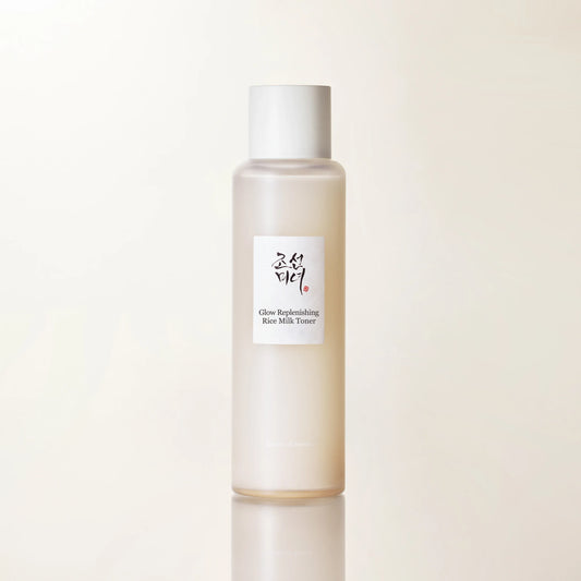 Close-up product shot emphasizing hydrating rice toner with warm beige minimal skincare branding and water splash base.