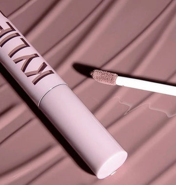 Kylie Cosmetics liquid lipstick tube with applicator wand on textured nude background from ZARÉ Cosmetics