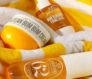 Sol de Janeiro Brazilian Bum Bum Cream, body oil, and Cheirosa 62 perfume mist on a beach towel at ZARÉ Cosmetics