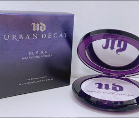 Urban Decay De-Slick mattifying powder compact and purple box packaging on ZARÉ Cosmetics